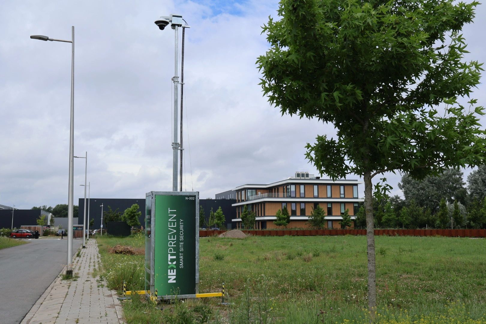 Cameramast bij een leegstaand terrein naast een kantoorpand